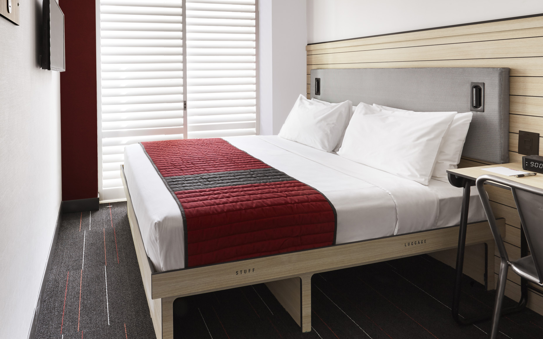 Queen bed with red and white cover in small room